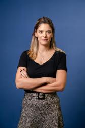 Paula Paschoal, diretora sênior do PayPal Brasil, de braços cruzados, com fundo azul por trás e com um leve sorriso no rosto